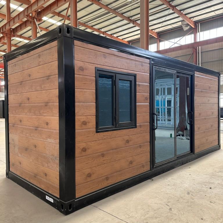 Portable wooden cabin with sliding glass door and window in a factory setting
