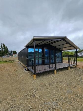 40 ft modular home with full-glass front and gable-roof deck installed on rural section in New Zealand